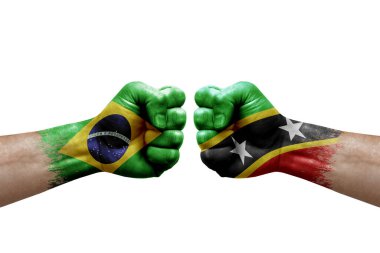 Two hands punch to each others on white background. Country flags painted fists, conflict crisis concept between brazil and saint kitts and nevis