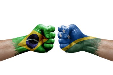 Two hands punch to each others on white background. Country flags painted fists, conflict crisis concept between brazil and solomon islands