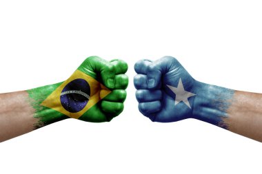 Two hands punch to each others on white background. Country flags painted fists, conflict crisis concept between brazil and somalia