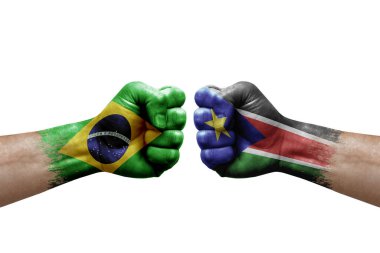 Two hands punch to each others on white background. Country flags painted fists, conflict crisis concept between brazil and south sudan