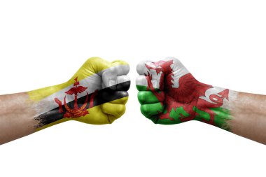 Two hands punch to each others on white background. Country flags painted fists, conflict crisis concept between brunei and wales