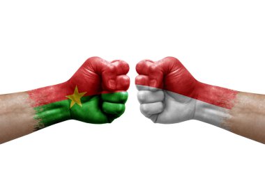 Two hands punch to each others on white background. Country flags painted fists, conflict crisis concept between burkina faso and indonesia