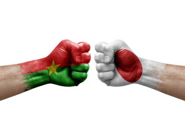 Two hands punch to each others on white background. Country flags painted fists, conflict crisis concept between burkina faso and japan