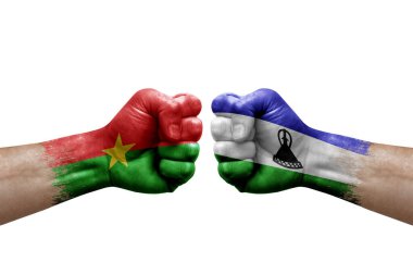 Two hands punch to each others on white background. Country flags painted fists, conflict crisis concept between burkina faso and lesotho