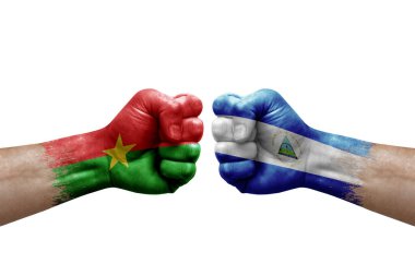 Two hands punch to each others on white background. Country flags painted fists, conflict crisis concept between burkina faso and nicaragua