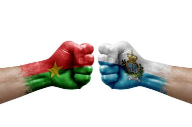 Two hands punch to each others on white background. Country flags painted fists, conflict crisis concept between burkina faso and san marino