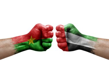 Two hands punch to each others on white background. Country flags painted fists, conflict crisis concept between burkina faso and united arab emirates
