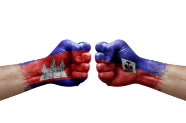 Two hands punch to each others on white background. Country flags painted fists, conflict crisis concept between cambodia and haiti