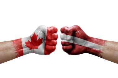 Two hands punch to each others on white background. Country flags painted fists, conflict crisis concept between canada and latvia