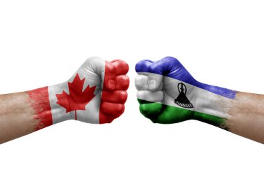 Two hands punch to each others on white background. Country flags painted fists, conflict crisis concept between canada and lesotho