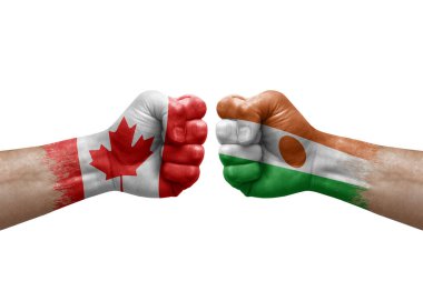 Two hands punch to each others on white background. Country flags painted fists, conflict crisis concept between canada and niger
