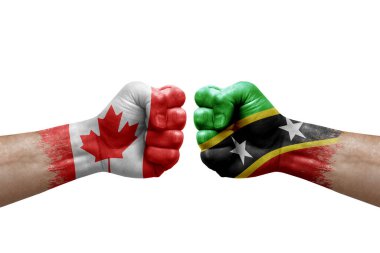 Two hands punch to each others on white background. Country flags painted fists, conflict crisis concept between canada and saint kitts and nevis