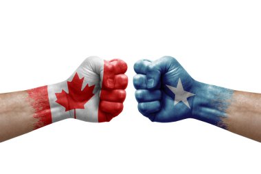 Two hands punch to each others on white background. Country flags painted fists, conflict crisis concept between canada and somalia