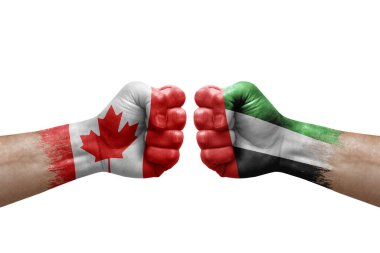 Two hands punch to each others on white background. Country flags painted fists, conflict crisis concept between canada and united arab emirates