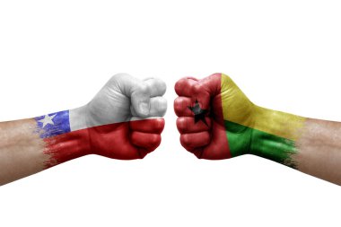 Two hands punch to each others on white background. Country flags painted fists, conflict crisis concept between chile and guinea-bissau