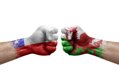 Two hands punch to each others on white background. Country flags painted fists, conflict crisis concept between chile and wales