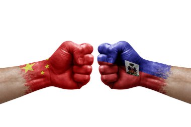 Two hands punch to each others on white background. Country flags painted fists, conflict crisis concept between china and haiti