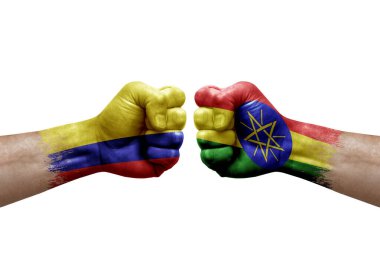Two hands punch to each others on white background. Country flags painted fists, conflict crisis concept between colombia and ethiopia
