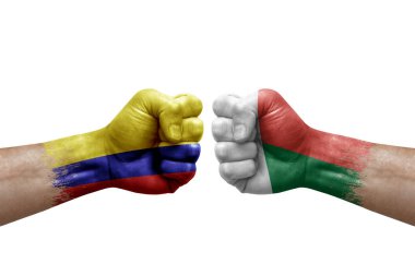 Two hands punch to each others on white background. Country flags painted fists, conflict crisis concept between colombia and madagascar