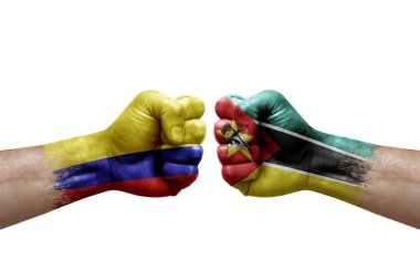 Two hands punch to each others on white background. Country flags painted fists, conflict crisis concept between colombia and mozambique
