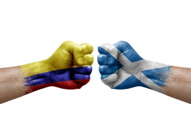 Two hands punch to each others on white background. Country flags painted fists, conflict crisis concept between colombia and scotland