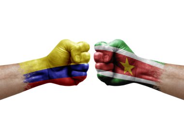 Two hands punch to each others on white background. Country flags painted fists, conflict crisis concept between colombia and suriname