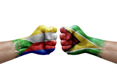 Two hands punch to each others on white background. Country flags painted fists, conflict crisis concept between comoros and guyana