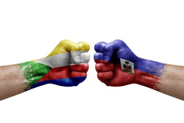 Two hands punch to each others on white background. Country flags painted fists, conflict crisis concept between comoros and haiti
