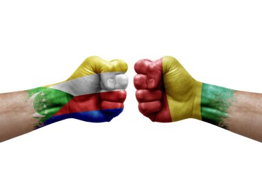Two hands punch to each others on white background. Country flags painted fists, conflict crisis concept between comoros and guinea