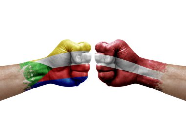 Two hands punch to each others on white background. Country flags painted fists, conflict crisis concept between comoros and latvia