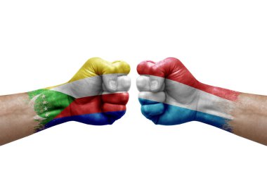 Two hands punch to each others on white background. Country flags painted fists, conflict crisis concept between comoros and luxembourg