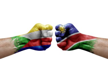Two hands punch to each others on white background. Country flags painted fists, conflict crisis concept between comoros and namibia