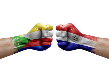 Two hands punch to each others on white background. Country flags painted fists, conflict crisis concept between comoros and paraguay