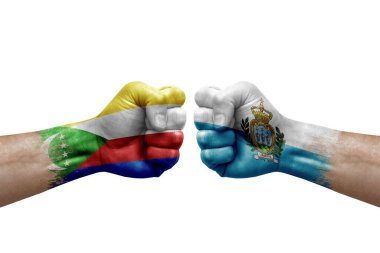 Two hands punch to each others on white background. Country flags painted fists, conflict crisis concept between comoros and san marino