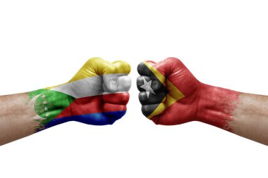 Two hands punch to each others on white background. Country flags painted fists, conflict crisis concept between comoros and timor leste