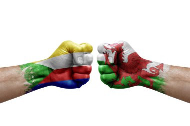 Two hands punch to each others on white background. Country flags painted fists, conflict crisis concept between comoros and wales