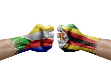 Two hands punch to each others on white background. Country flags painted fists, conflict crisis concept between comoros and zimbabwe