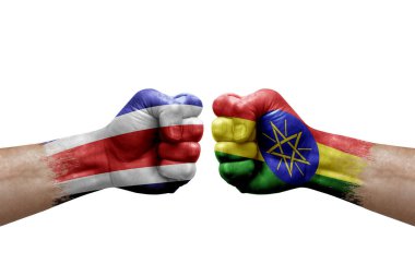Two hands punch to each others on white background. Country flags painted fists, conflict crisis concept between costa rica and ethiopia