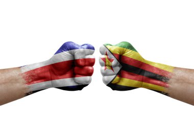 Two hands punch to each others on white background. Country flags painted fists, conflict crisis concept between costa rica and zimbabwe