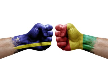 Two hands punch to each others on white background. Country flags painted fists, conflict crisis concept between curacao and guinea