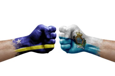 Two hands punch to each others on white background. Country flags painted fists, conflict crisis concept between curacao and san marino
