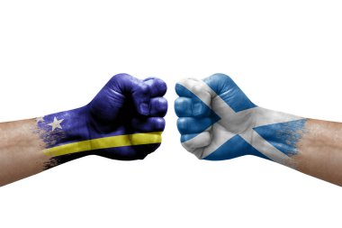 Two hands punch to each others on white background. Country flags painted fists, conflict crisis concept between curacao and scotland