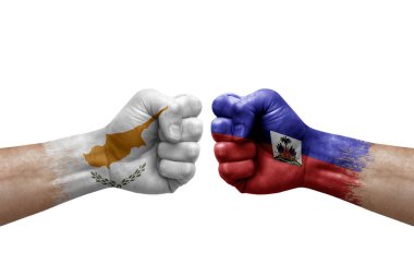 Two hands punch to each others on white background. Country flags painted fists, conflict crisis concept between cyprus and haiti