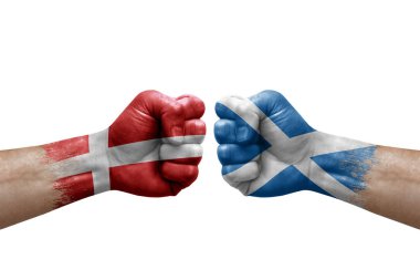 Two hands punch to each others on white background. Country flags painted fists, conflict crisis concept between denmark and scotland