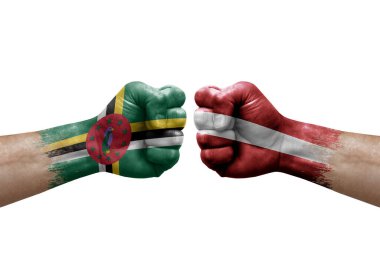 Two hands punch to each others on white background. Country flags painted fists, conflict crisis concept between dominica and latvia
