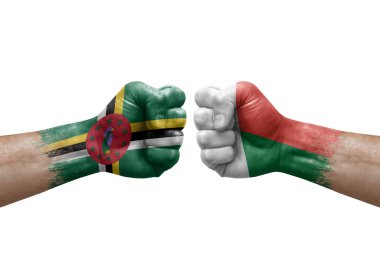 Two hands punch to each others on white background. Country flags painted fists, conflict crisis concept between dominica and madagascar