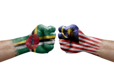 Two hands punch to each others on white background. Country flags painted fists, conflict crisis concept between dominica and malaysia