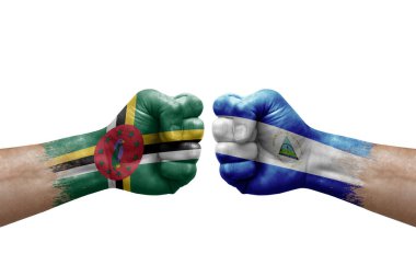 Two hands punch to each others on white background. Country flags painted fists, conflict crisis concept between dominica and nicaragua