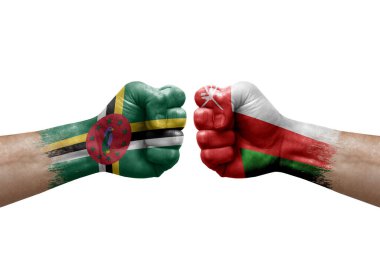 Two hands punch to each others on white background. Country flags painted fists, conflict crisis concept between dominica and oman