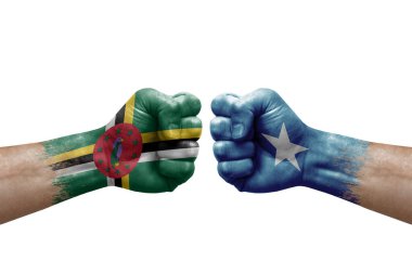 Two hands punch to each others on white background. Country flags painted fists, conflict crisis concept between dominica and somalia